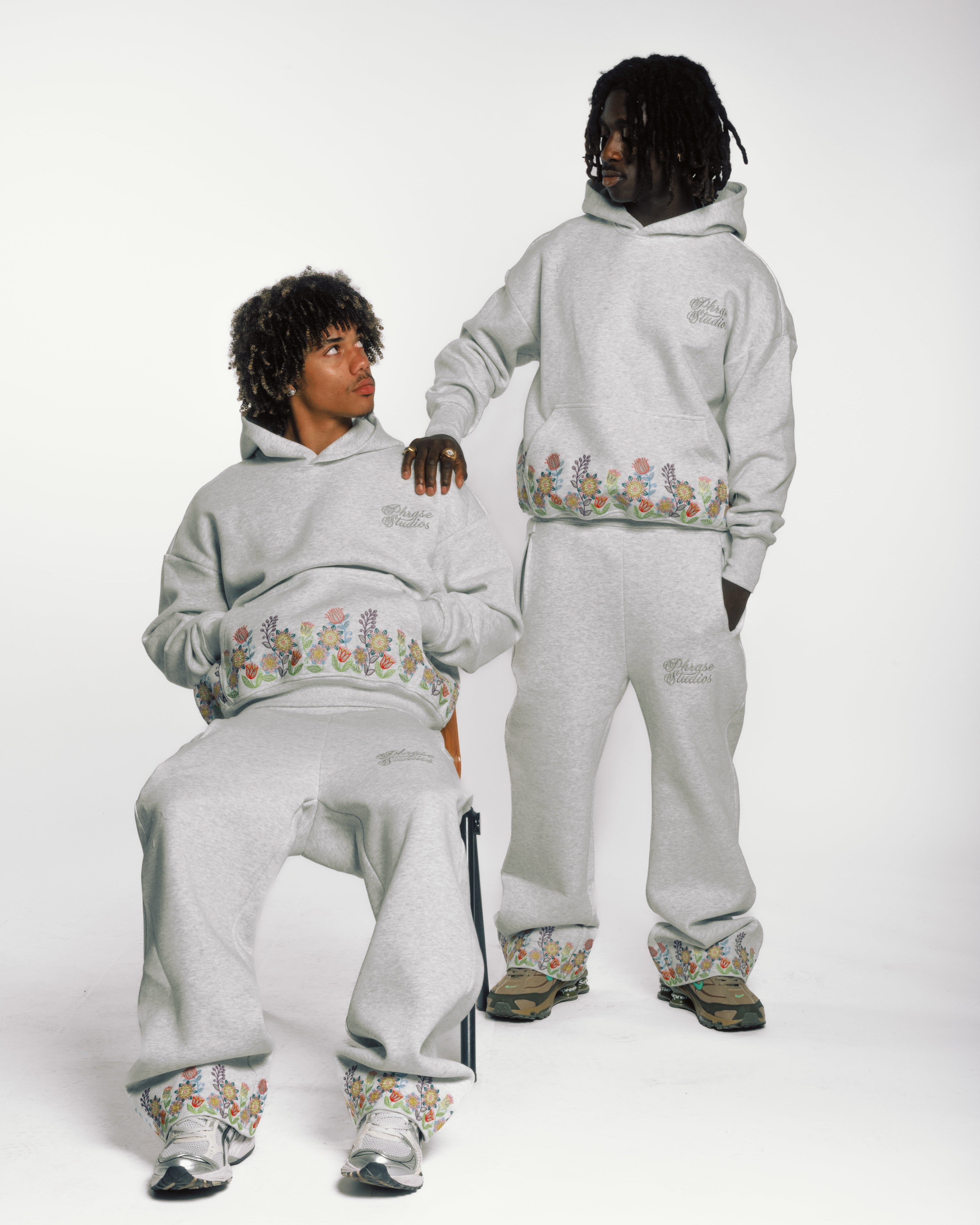 Two models in gray floral embroidered hoodies and sweatpants for activewear