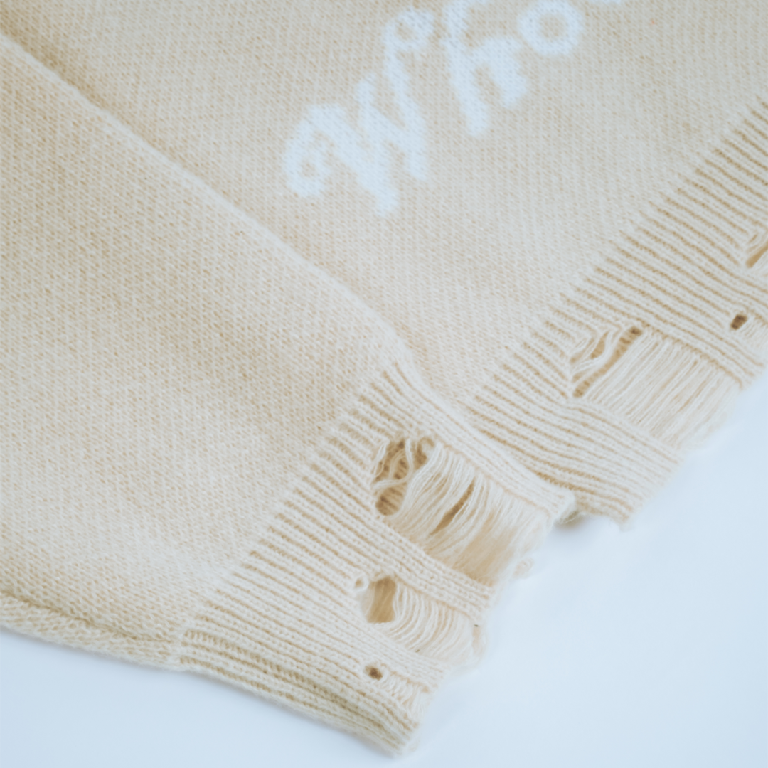 Detail of distressed hem and tag on Devil & Angel Knit sweater