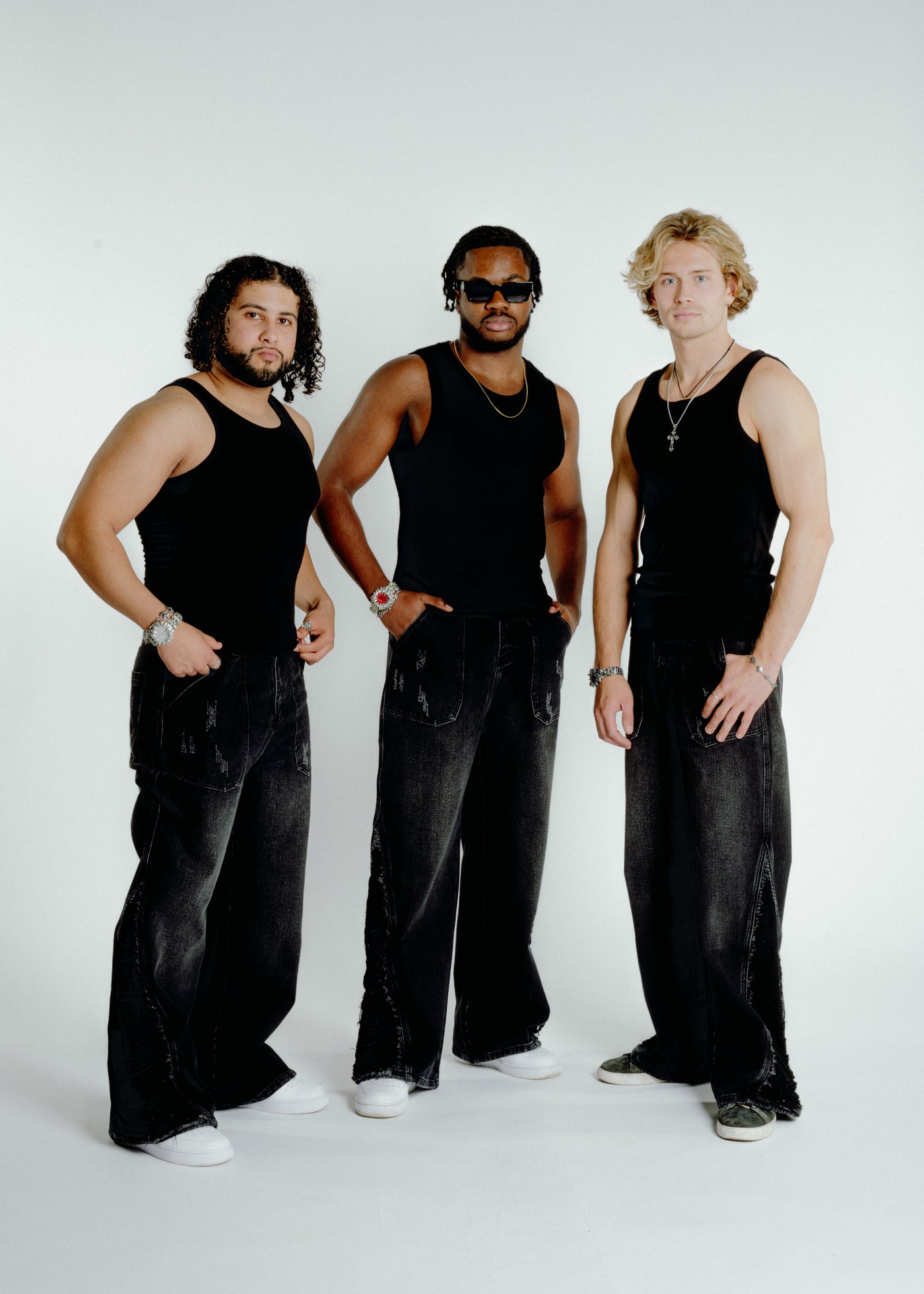 Group of three models wearing black jeans and tank tops, casual streetwear style