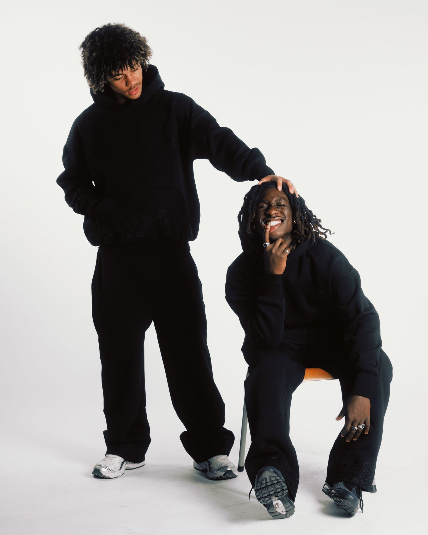Models wearing black embroidered hoodies and track pants