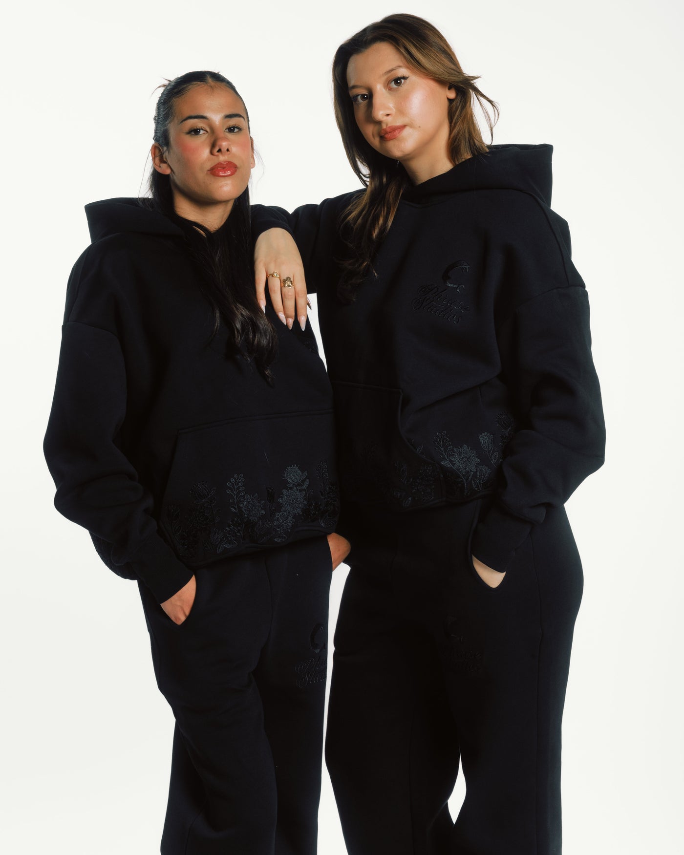Two models in black embroidered activewear hoodies